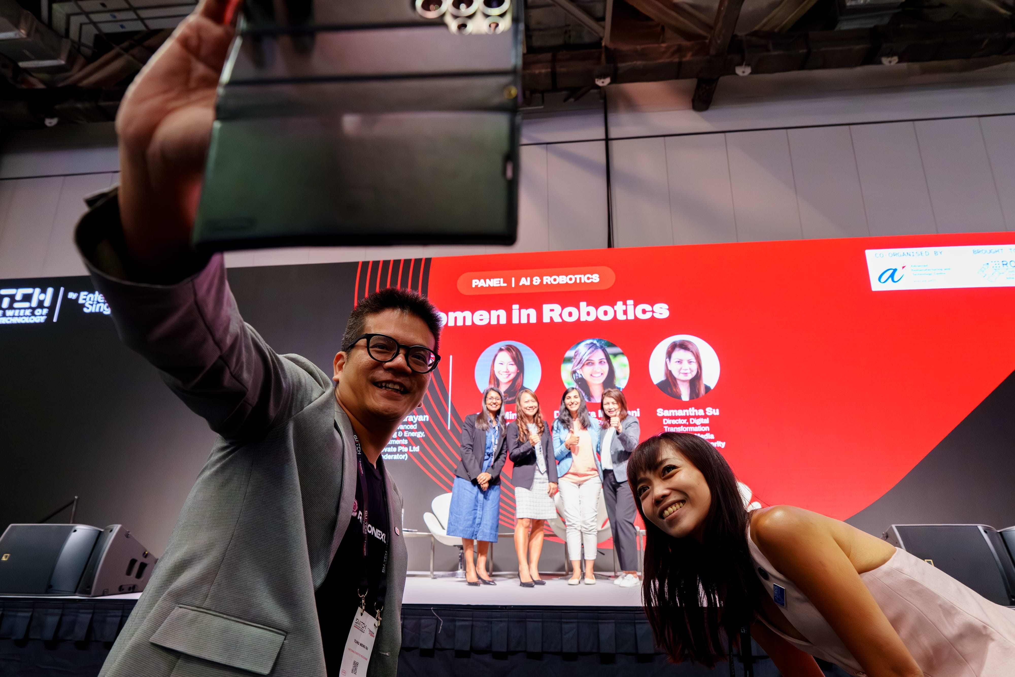 Person taking a selfie with the panelists lined up on stage